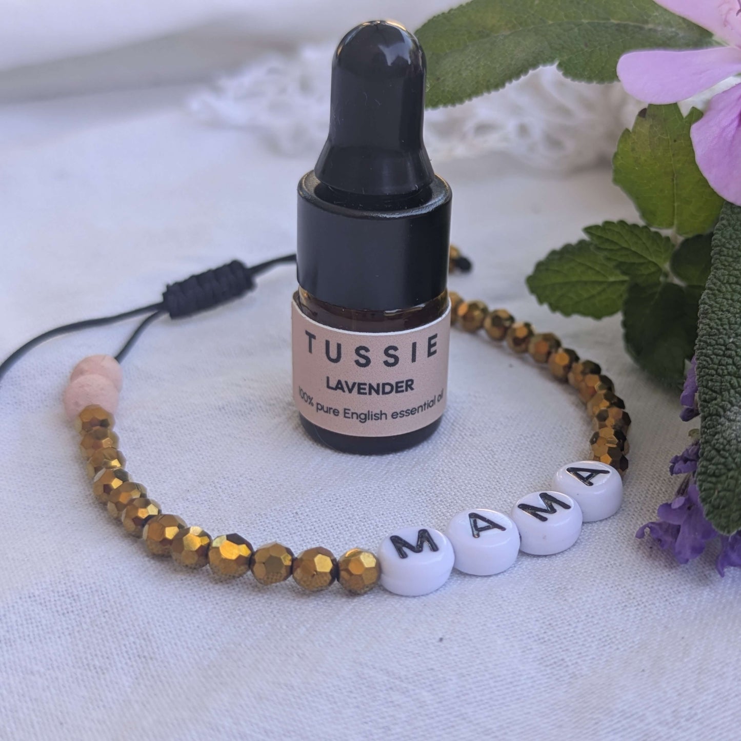 Bottle of Tussie Lavender essential oil with a beaded bracelet on a white background